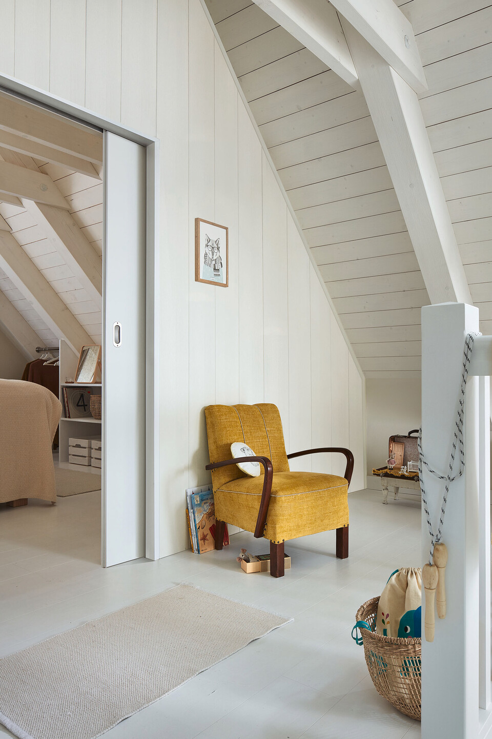 Wohnraum mit Dachschrägen und Deckenvertäfelung aus weißem Holz