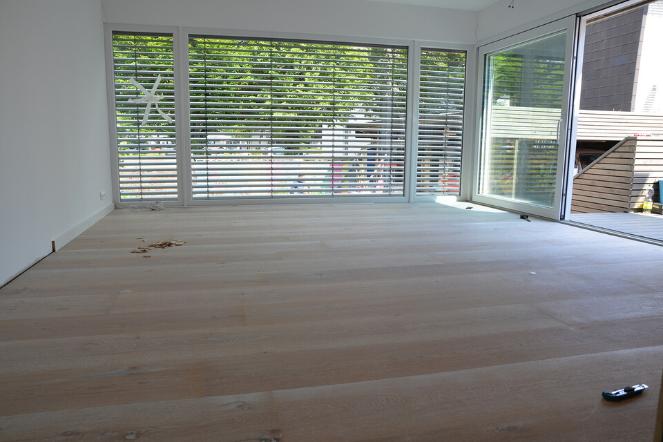 Heller Lindura-Holzboden in einem neuen Anbau mit Fußbodenheizung und großen Fenstern