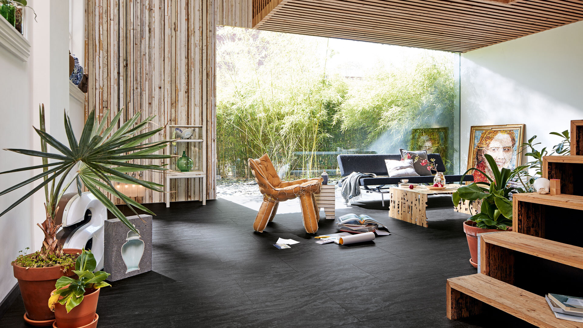 Schwarzer Designboden im Kontrast zu viel Holz und Grünpflanzen im Tropcial Style